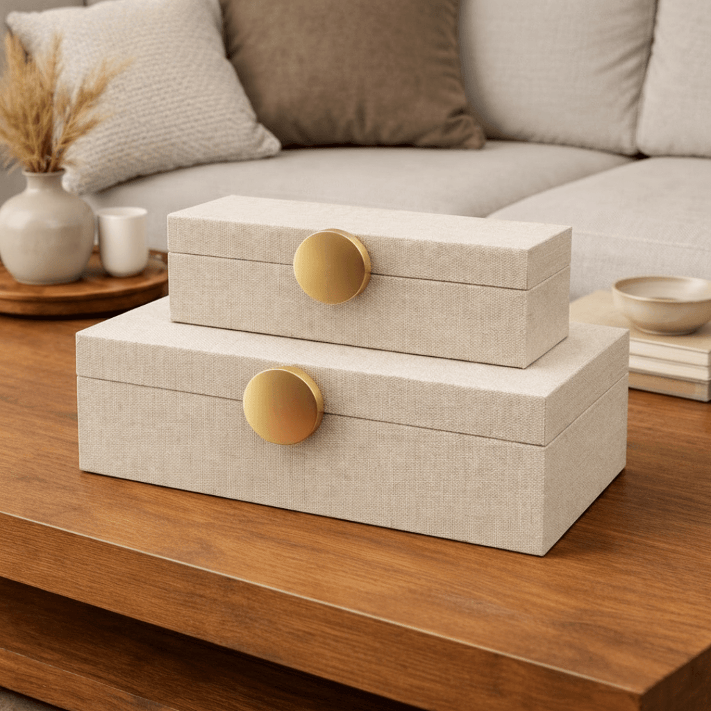 Kit 2 caixas decorativas em MDF bege com puxador dourado sobre mesa de centro de sala de estar