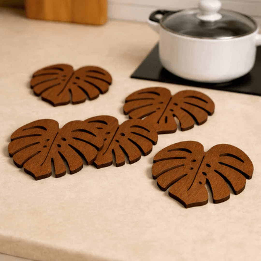 Porta-copos formato folha Monstera em madeira sobre mesa de jantar