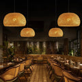 Luminária pendente cesto em bambu natural sobre mesa de restaurante