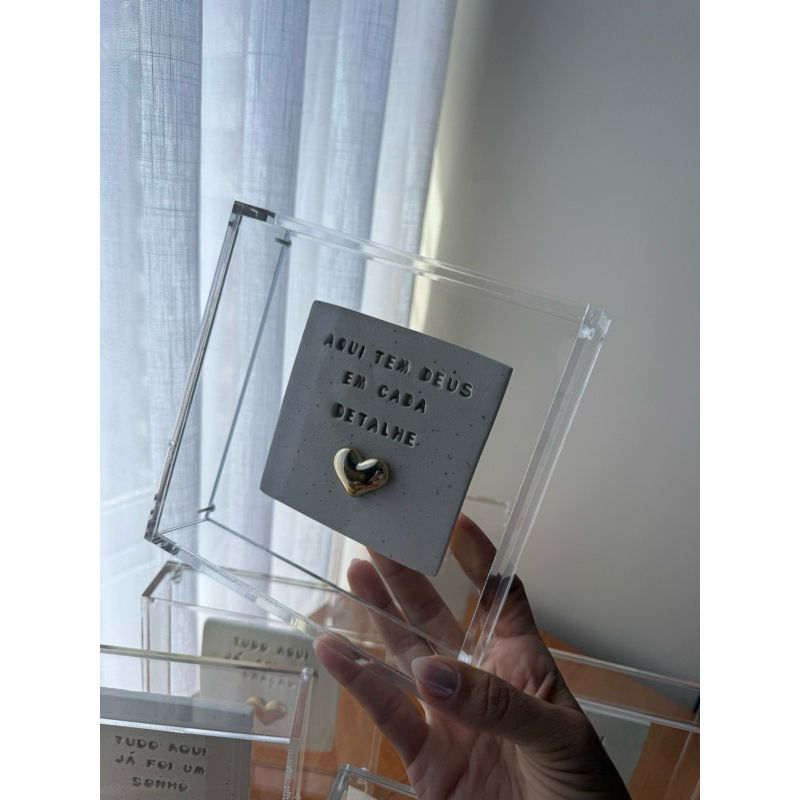 Quadro de Acrílico com placa de cerâmica “ Aqui tem Deus em cada detalhe ”. o modelo de coração pode variar